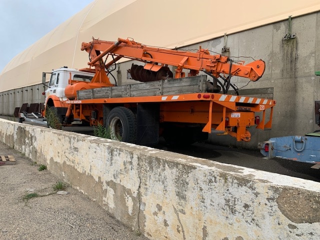 Zoomed out view of truck with heavy equipment up for auction at Maltz Auctions